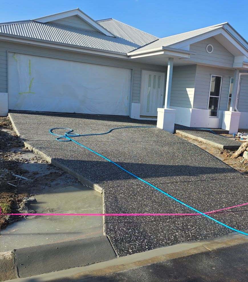 Charcoal exposed aggregate driveway on a new home with the setout lines still up, Sunshine Coast