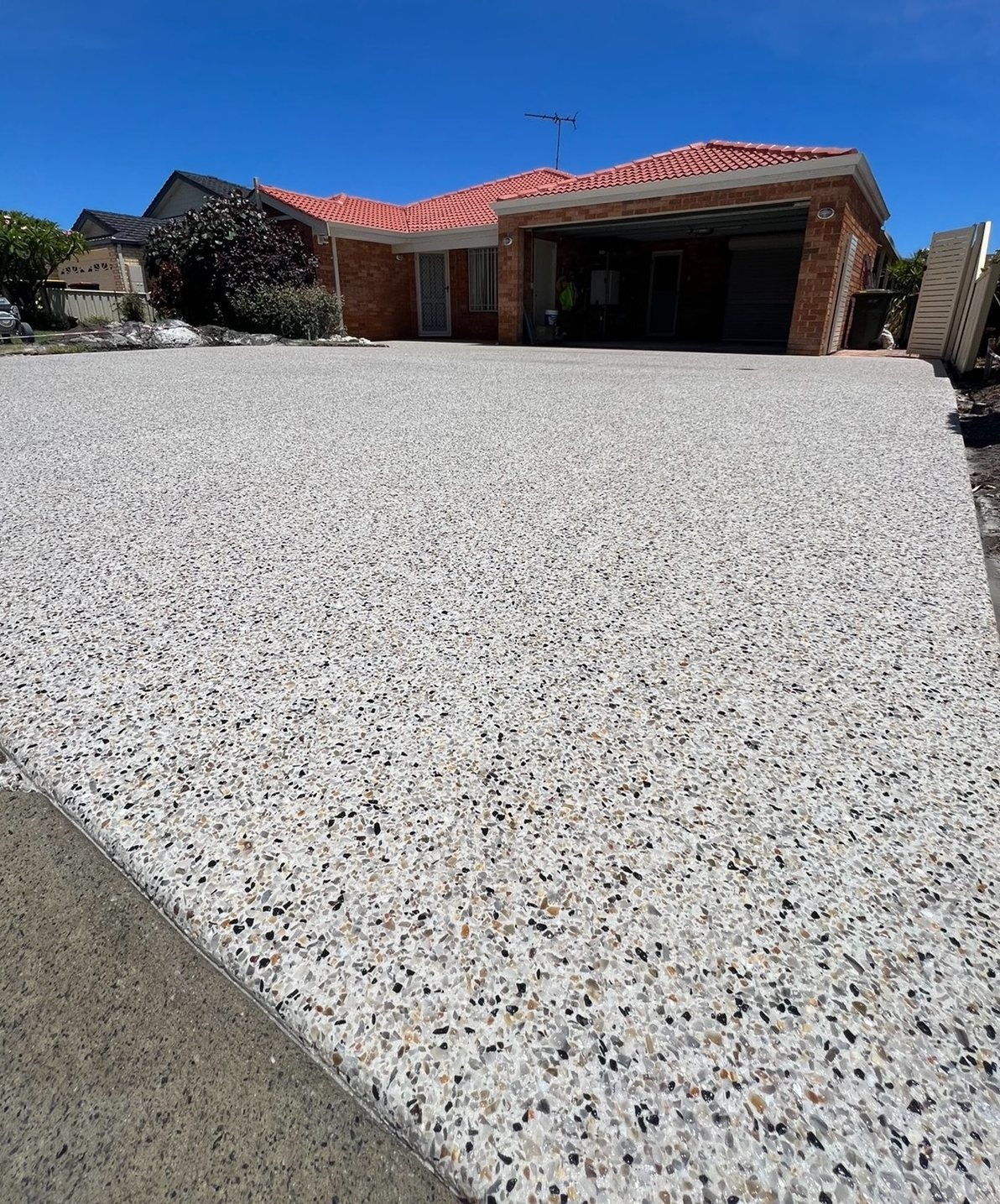 Exposed aggregate concrete driveway surface after washing and sealing