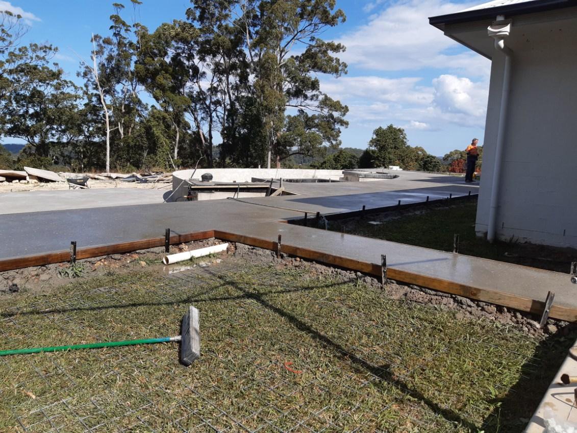 Outdoor concrete slab formed to a straight timber edge beside a house, Sunshine Coast